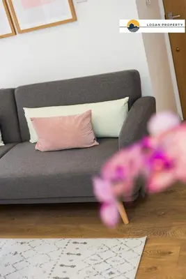 a gray couch with a pink pillow and purple flowers at Lady Wynd - 1 bed apartment in Edinburgh