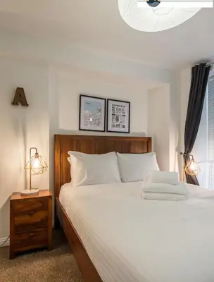 a bedroom with a large white bed with a wooden headboard at Lady Wynd - 1 bed apartment in Edinburgh