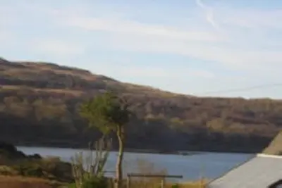 a lake with a tree in front of a mountain at Glenview Salen in Salen