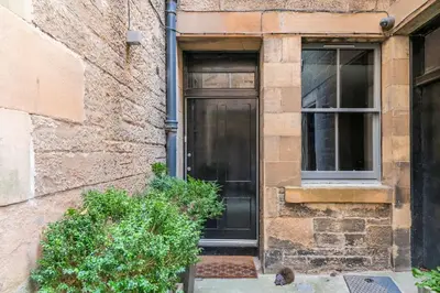 a black door on a brick building with a window at Immaculate 3 Bed Apartment with Private Entrance in Inverleith in Edinburgh