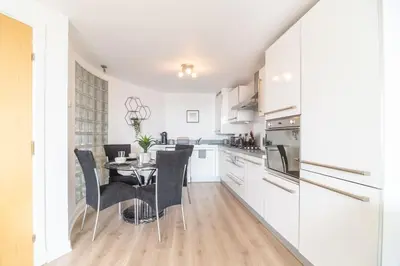 a kitchen with white cabinets and a table and chairs at Luxury Riverview City Centre Apartment 2 in Glasgow