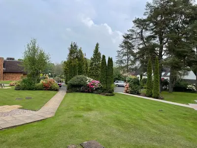 a yard with green grass and flowers and trees at Gleneagles Rental in Auchterarder