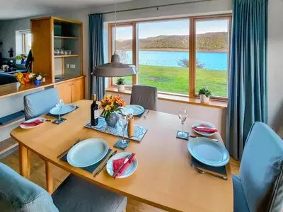 a dining room with a table and a large window at Tulamain in Ardfern