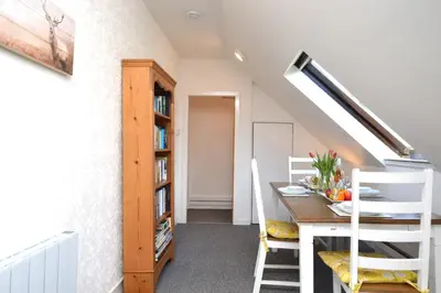 a dining room with a table and a book shelf at Heronlea Cottage in Dunoon