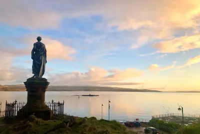 a statue of a man standing in front of a body of water at Heronlea Cottage in Dunoon