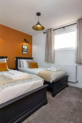 a bedroom with two beds and a window at The Stylish 3-Bedroom Maisonette Retreat in Stirling