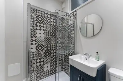 a bathroom with a shower with a sink and a mirror at James Street 2 Bedroom Apartment in Stirling