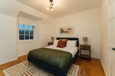 a bedroom with a large bed and a window at The Old Deanston Workers Cottage in Doune