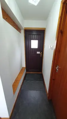 a hallway with a wooden door and a small window at Rhumhor in Bunessan