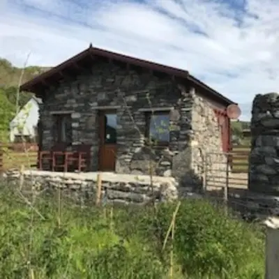 a stone cabin with a red door in a field at Ardchiavaig Cabin in Uisken