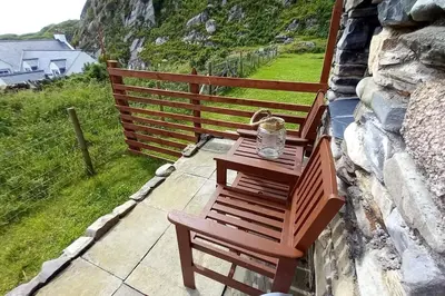 a wooden bench sitting on top of a stone wall at Ardchiavaig Cabin in Uisken