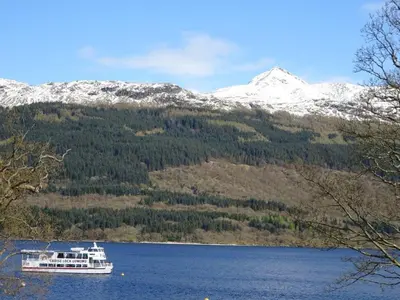 a boat on a lake in front of a mountain at 2 Bed in Lochgilphead AG577 in Kilmartin