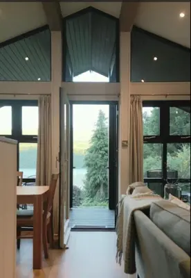 a bedroom with a bed and a table and a large window at Sixpenny Bay in Morenish
