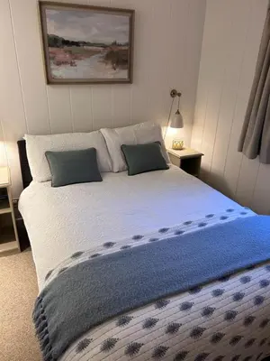 a bedroom with a large bed with a blue blanket at Sixpenny Bay in Morenish