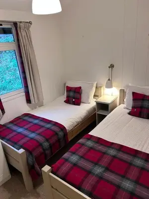 a bedroom with two beds and a window at Sixpenny Bay in Morenish