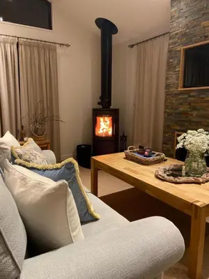 a living room with a fireplace and a wooden table at Sixpenny Bay in Morenish