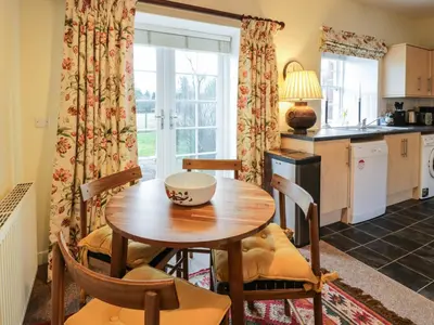 a kitchen and dining room with a wooden table and chairs at The Stables in Dumfries