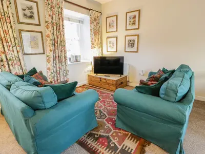 a living room with two blue couches and a television at The Stables in Dumfries