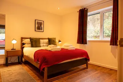 a bedroom with a bed with a red blanket at Cairn Cottage in Onich