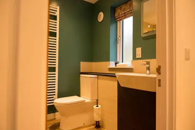 a green bathroom with a toilet and a sink at Cairn Cottage in Onich