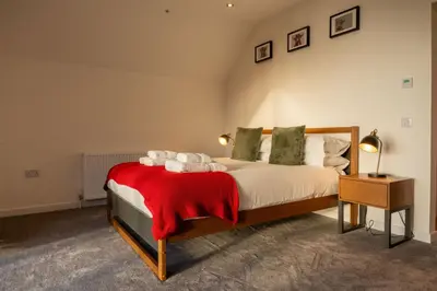 a bedroom with a bed with a red blanket at Cairn Cottage in Onich