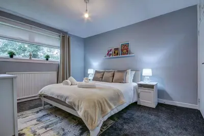 a bedroom with a large bed and a window at Ravenscroft - Coorie Doon in Irvine