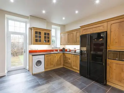 a kitchen with wooden cabinets and a black refrigerator at 5 Bed in Brodick CA016 in Brodick