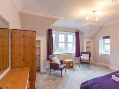 a bedroom with a bed and two chairs and a table at 5 Bed in Brodick CA016 in Brodick