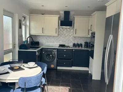 a kitchen with white cabinets and a table with blue chairs at Tigh Lochlainn in Prestwick