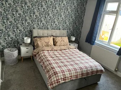 a bedroom with a bed with a plaid blanket at Tigh Lochlainn in Prestwick