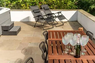 a wooden table with wine glasses on a patio at Stunning Dalchenna w/hot tub & huge garden in Stirling