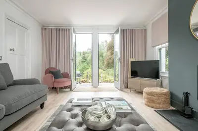 a living room with a couch and a tv at Stunning Dalchenna w/hot tub & huge garden in Stirling
