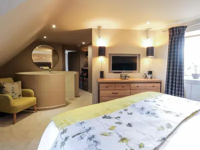 a bedroom with a large bed and a television at Shepherdess Cottage in Moffat