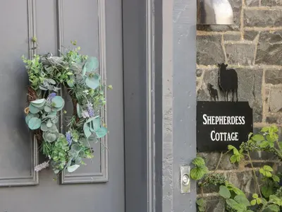 a door with a sign on it with plants on it at Shepherdess Cottage in Moffat