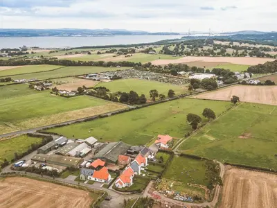 an aerial view of a village with a field and water at The Old Mill in Linlithgow