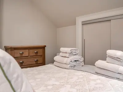 a bedroom with a stack of towels on a bed at Pride Of Erin - Uk45929 in Linlithgow