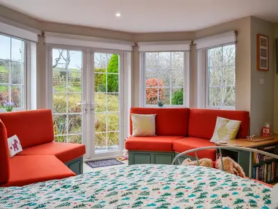 a bedroom with red chairs and a bed and windows at The Smithy in New Galloway