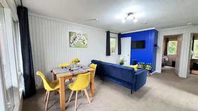 a living room with a table and a blue couch at Whisky Whispers Hunters Quay in Sandbank