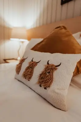 a pillow with two cows on it on a bed at Whisky Whispers Hunters Quay in Sandbank
