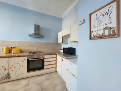 a kitchen with white cabinets and a sign on the wall at The Octopus - at Largs Town Centre with Private Parking in Largs