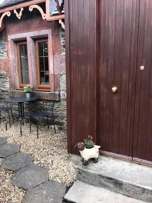 a wooden door of a house with a table and chairs at Alderdale B&B in Luss