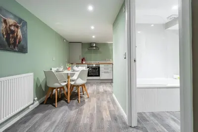 a kitchen and dining room with a table and chairs at Broom Cottage in Lanark