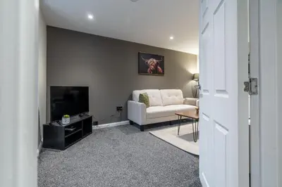 a living room with a white couch and a television at Broom Cottage in Lanark