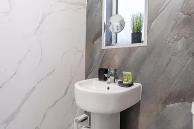 a bathroom with a white sink and a mirror at Kirkview Apartment in Kirk of Shotts