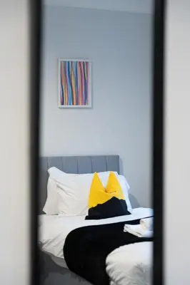 a mirror reflection of a bed with yellow and white pillows at Kirkview Apartment in Kirk of Shotts