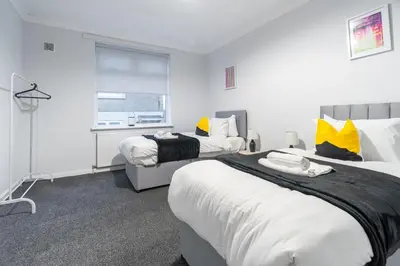 a hotel room with two beds and a window at Kirkview Apartment in Kirk of Shotts