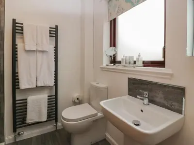 a white bathroom with a toilet and a sink at Hollys Hideaway in Castle Douglas