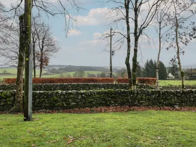 a stone wall in a park with trees and grass at Hollys Hideaway in Castle Douglas