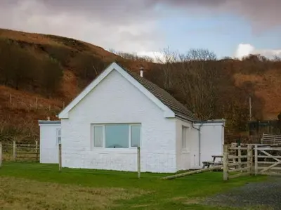 a white house with a fence in front of it at Ormsaig Byre in Beach