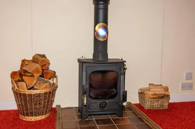 a black stove with a basket of wood at Ormsaig Byre in Beach
